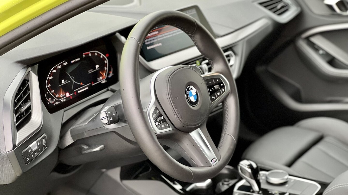 Auf der Mittelkonsole des M135i xDrive greift die Hand zum iDrive-Controller.